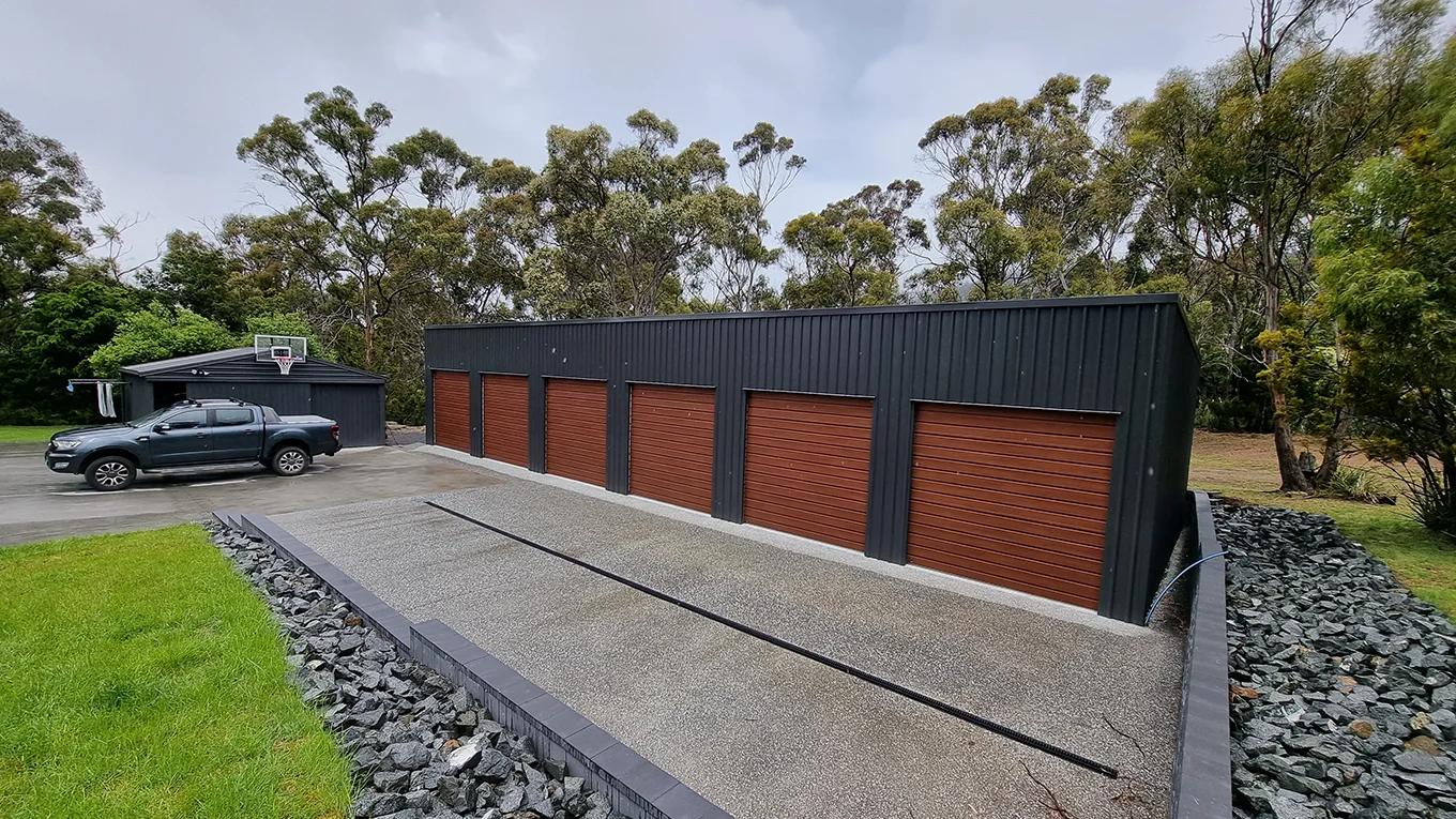 Six-bay garage with woodgrain roller doors and landscaped surrounds.