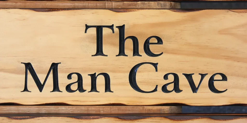 A wooden sign with 'The Man Cave' engraved in black letters.