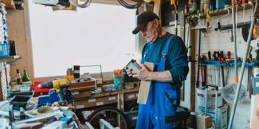 An elderly man working in a well-organised man cave workshop.