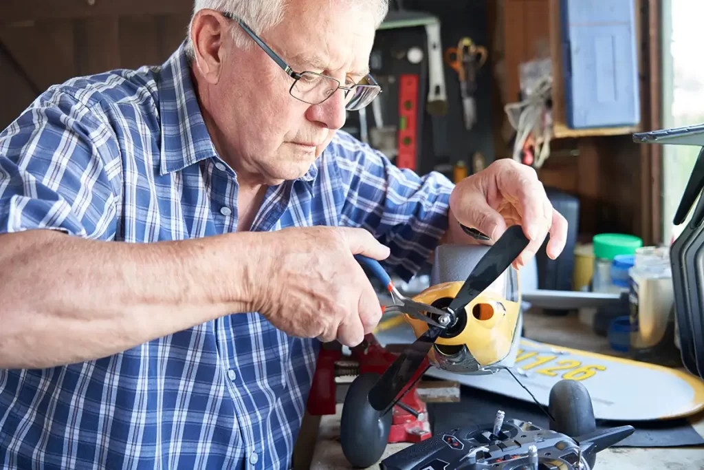 A man repairing a model plane in his man cave workshop.