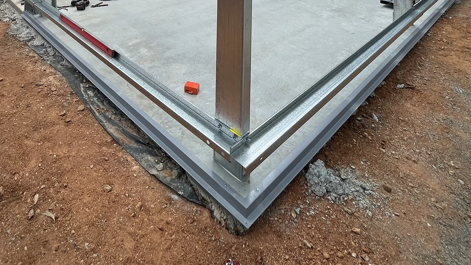 Installed vermin flashing at the base of a concrete slab on a steel shed