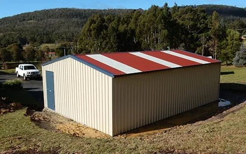 Photo of a colourful Colorbond shed clad in the colours of Classic Cream walls, Deep Ocean doors and Manor Red roof.