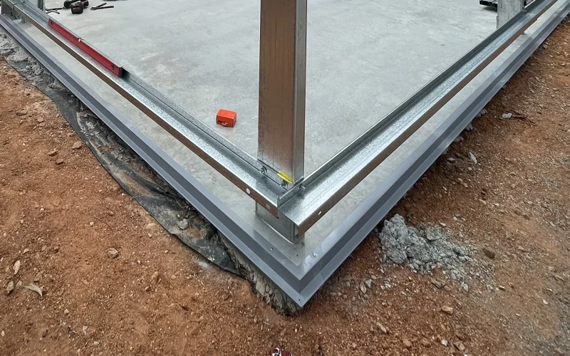 Installed vermin flashing at the base of a concrete slab on a steel shed