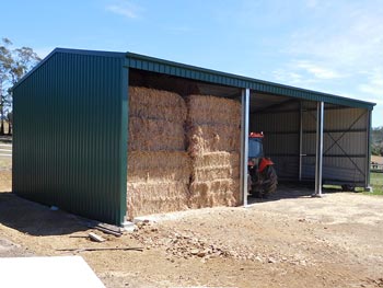 Photo of a 3 bay farm shed with hay and a tractor inside. Clad in Colorbond in Cottage Green