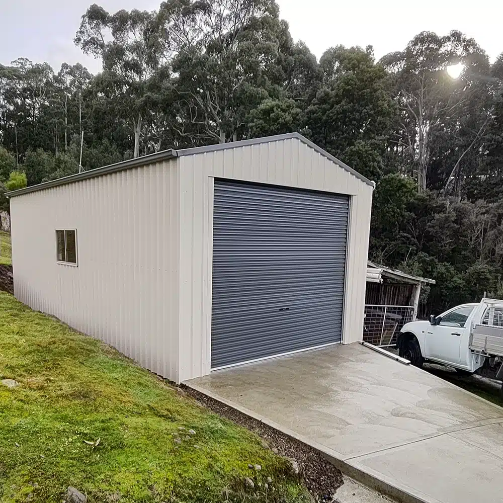 Photo of the whole Colorbond garage showin a window in the side and roller door on the end.