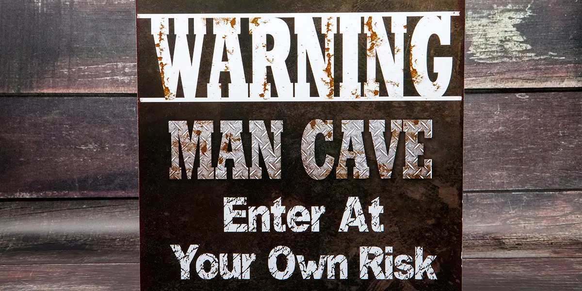 A rusted metal sign warning 'Man Cave - Enter at Your Own Risk.