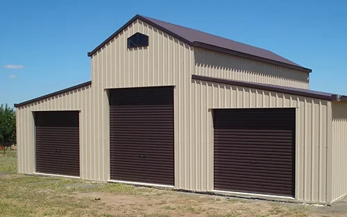 Photo of a Colorbond barn with three bays on the end of the barn. The barn has three roller doors in the end also.