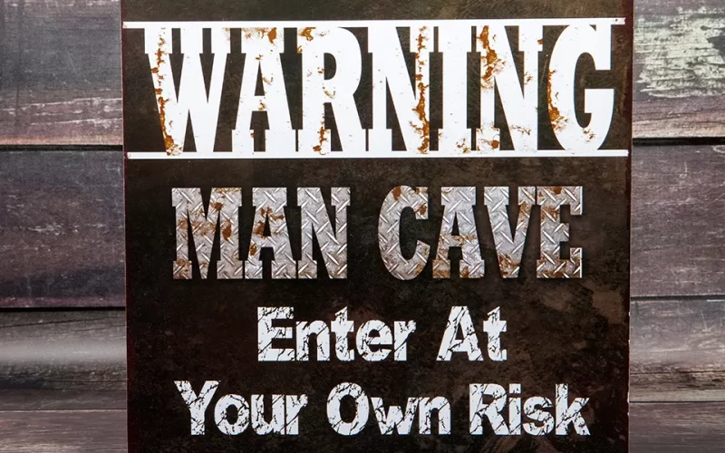 A rusted metal sign warning 'Man Cave - Enter at Your Own Risk.