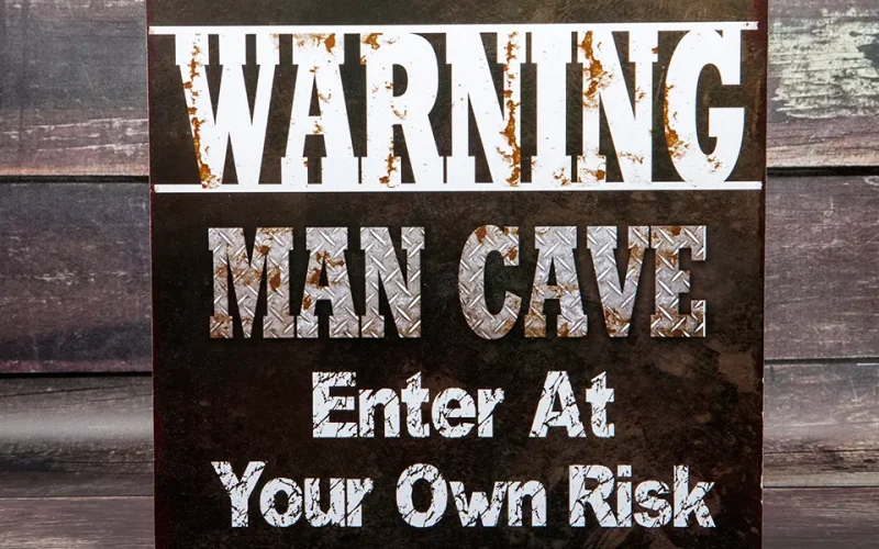 A rusted metal sign warning 'Man Cave - Enter at Your Own Risk.